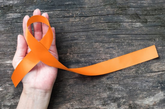 Hand holding an orange ribbon