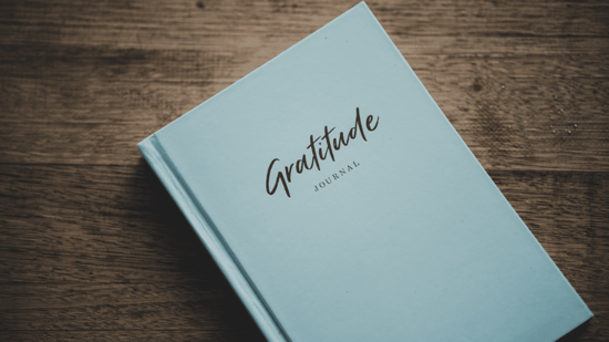 light blue gratitude journal on wooden surface