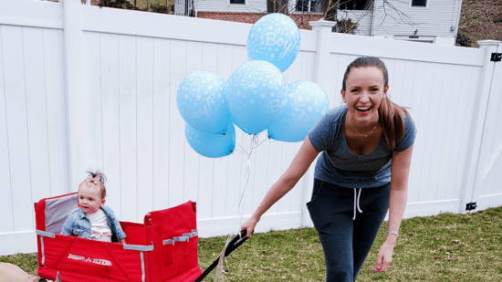 happy mom to be at gender reveal with toddler in wagon