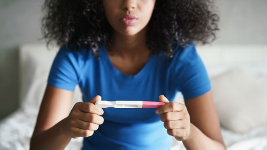woman holding pregnancy test in blue shirt